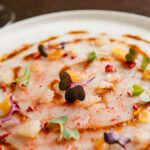 Carpaccio de gamba roja de Palamós, fruto rojos liofilizados, cítricos y aceite de su coral